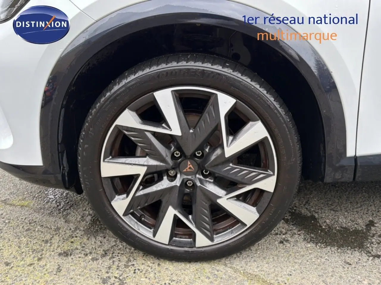 Gros plan sur la roue avant droite d’une CUPRA Formentor blanc neige métal avec jante bi-ton au design anguleux.