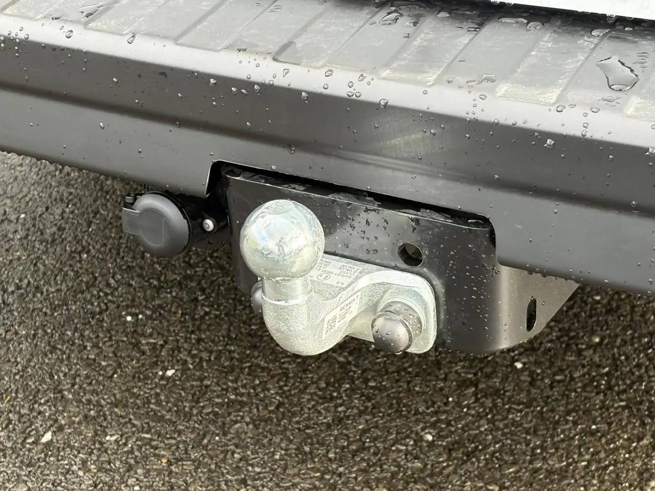 Gros plan sur l'attelage métallique sous le pare-chocs arrière gris d'un Renault Trafic Fourgon blanc glacier.