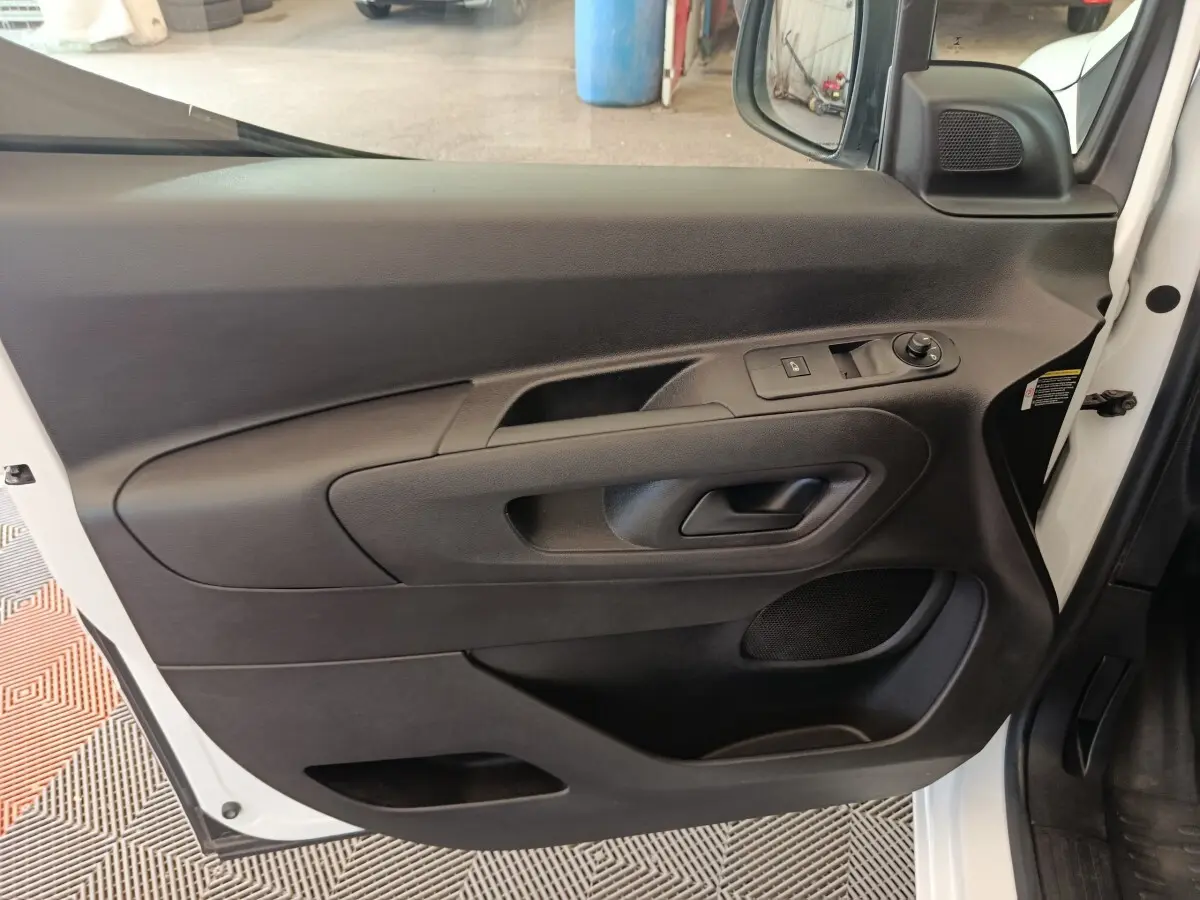 Vue intérieure côté gauche de la porte avant d’un Citroën Berlingo blanc 2021 avec commandes de vitre et miroir.