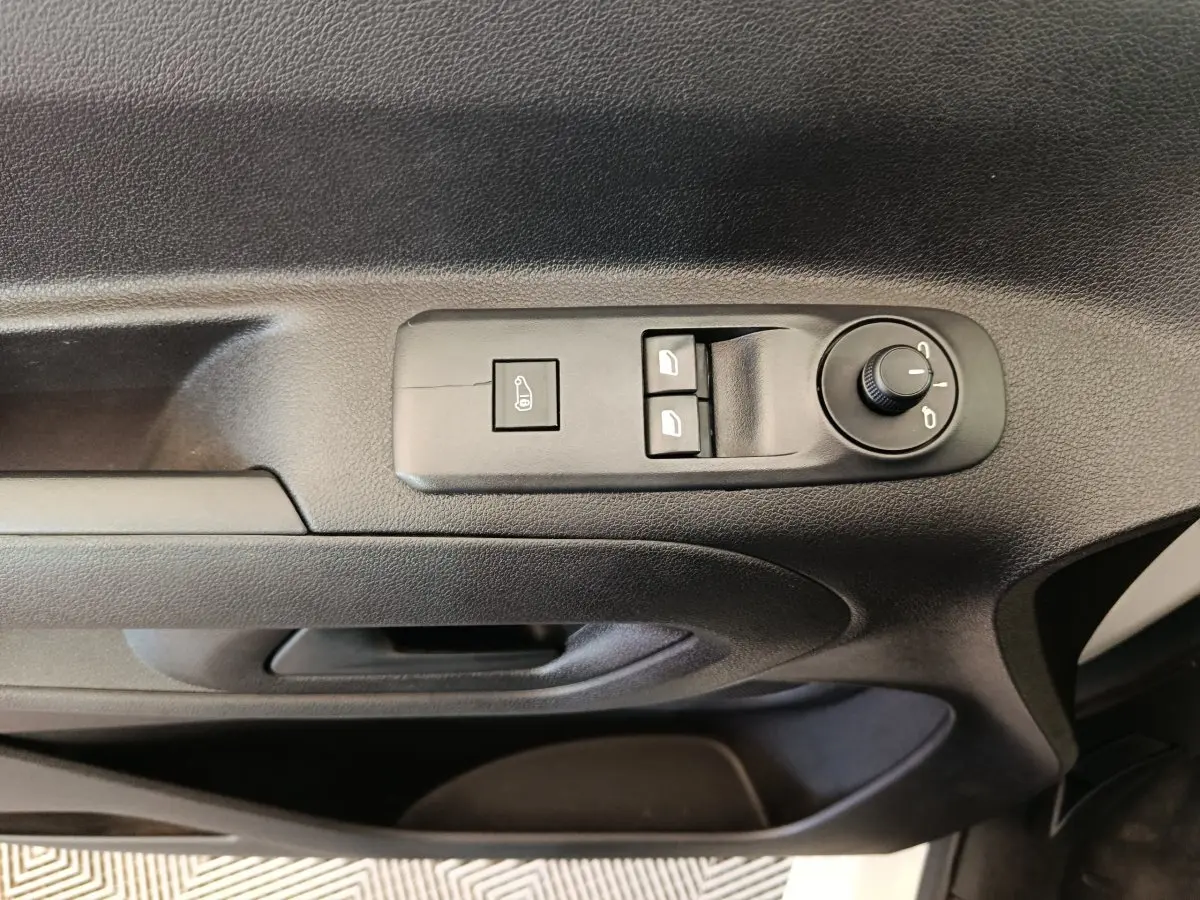 Détail de la commande de réglage des rétroviseurs sur la porte intérieure noire d'un Citroën Berlingo 2021.