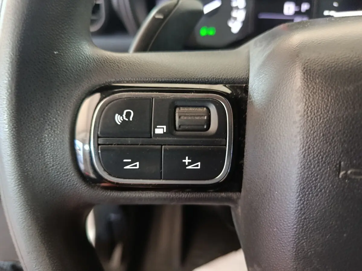 Gros plan sur les commandes au volant côté gauche du Citroën Berlingo blanc 2021, avec boutons de volume et appel.