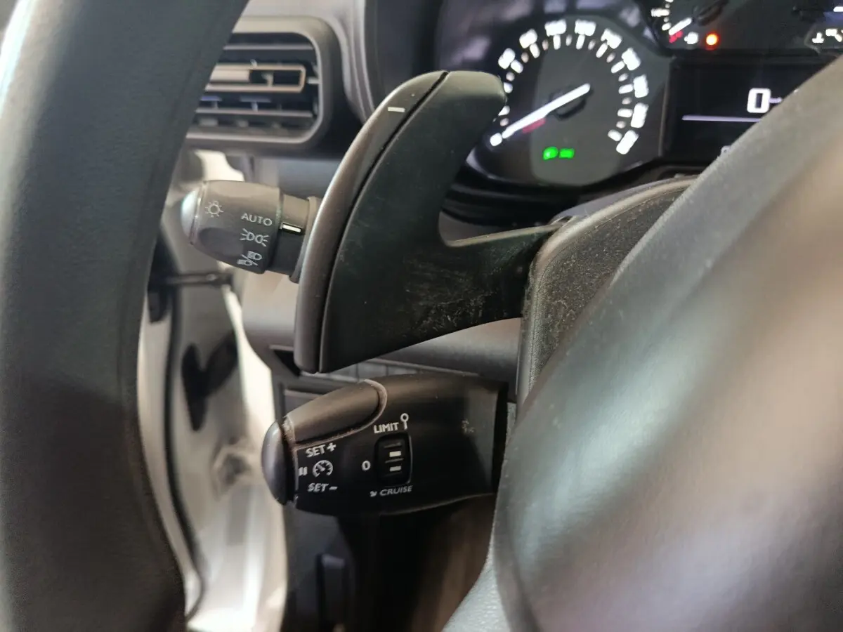 Gros plan sur la commande de régulateur de vitesse et palettes au volant d’un Citroën Berlingo blanc, vue côté gauche.