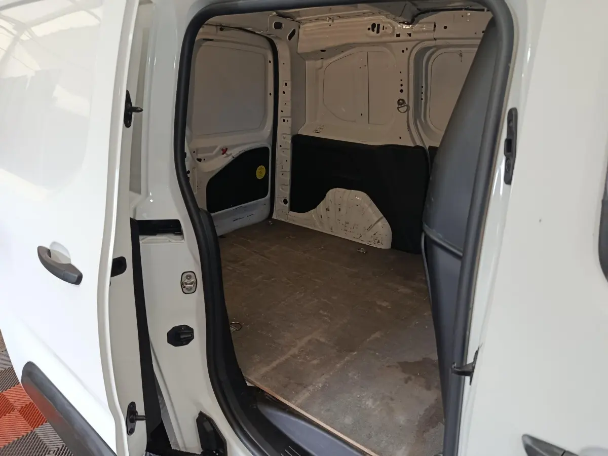 Vue intérieure de la partie arrière ouverte d’un Citroën Berlingo blanc 2021, montrant l’espace de chargement vide.