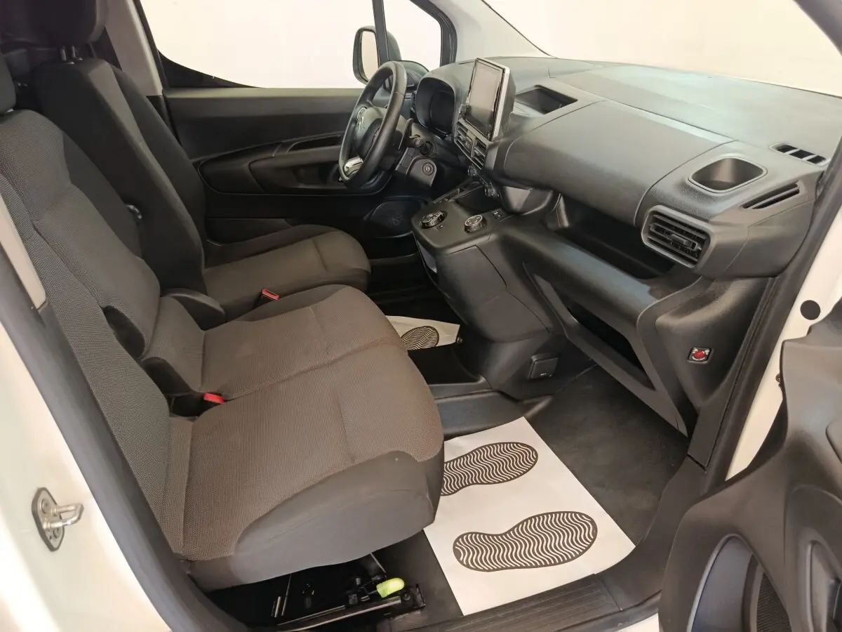 Vue intérieure côté conducteur du Citroën Berlingo blanc 2021, avec tableau de bord noir et sièges tissu gris.