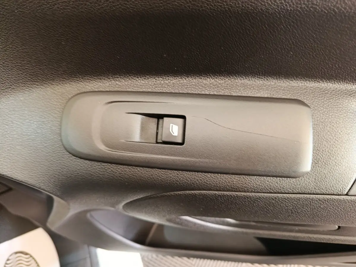 Gros plan sur l'interrupteur de lève-vitre côté conducteur dans l'intérieur noir du Citroën Berlingo blanc 2021.