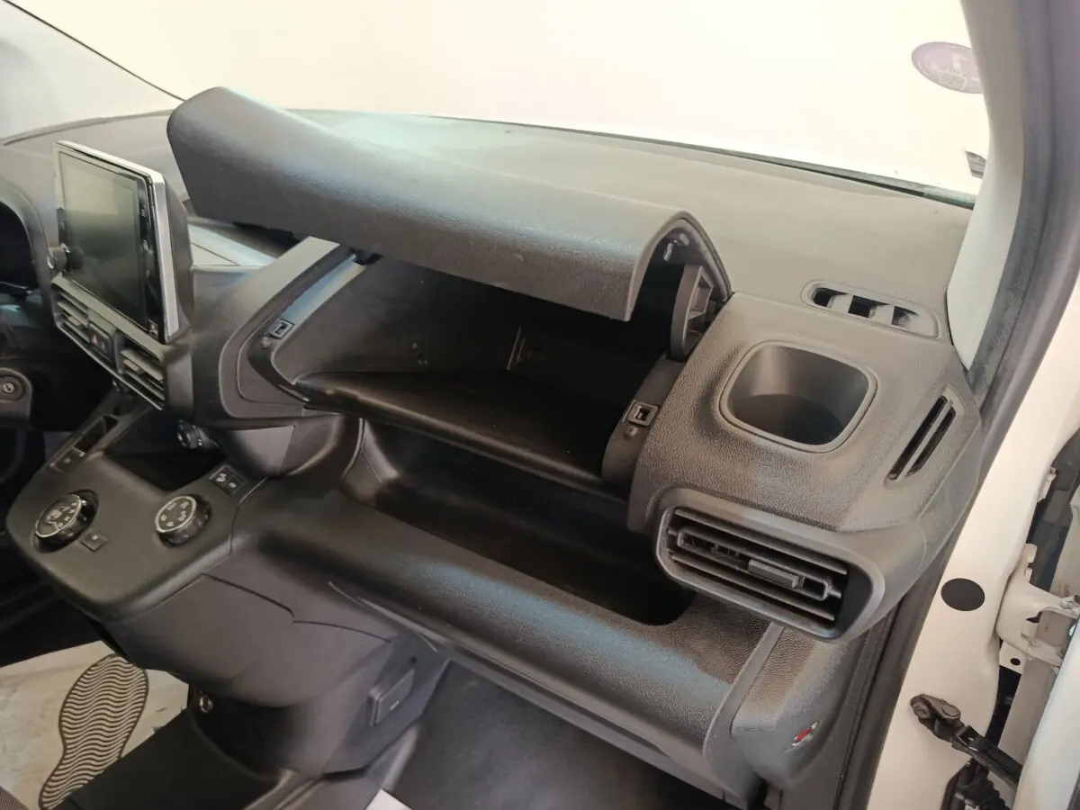 Intérieur du Citroën Berlingo 2021 blanc, vue côté passager montrant la boîte à gants ouverte et la console centrale noire.