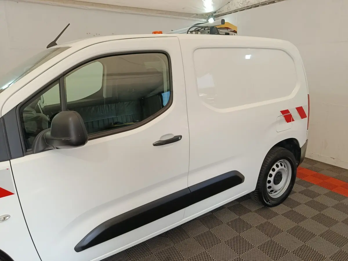 Vue de profil côté gauche d’un Citroën Berlingo blanc 2021 avec bandes rouges réfléchissantes et toit équipé d’un gyrophare.