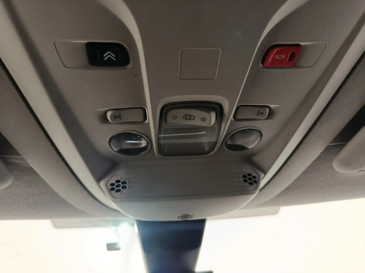 Vue en contre-plongée du plafonnier gris clair du Citroën Berlingo 2021 avec bouton SOS rouge et commandes d’éclairage.