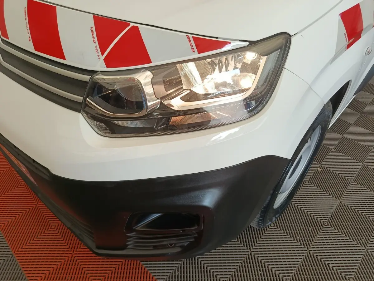 Gros plan sur l'avant droit blanc d'un Citroën Berlingo 2021 avec marquage rouge et blanc de sécurité.
