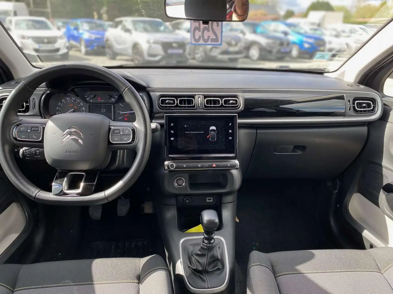 Vue intérieure avant du tableau de bord et volant de la Citroën C3 2021 avec écran tactile et boîte manuelle.
