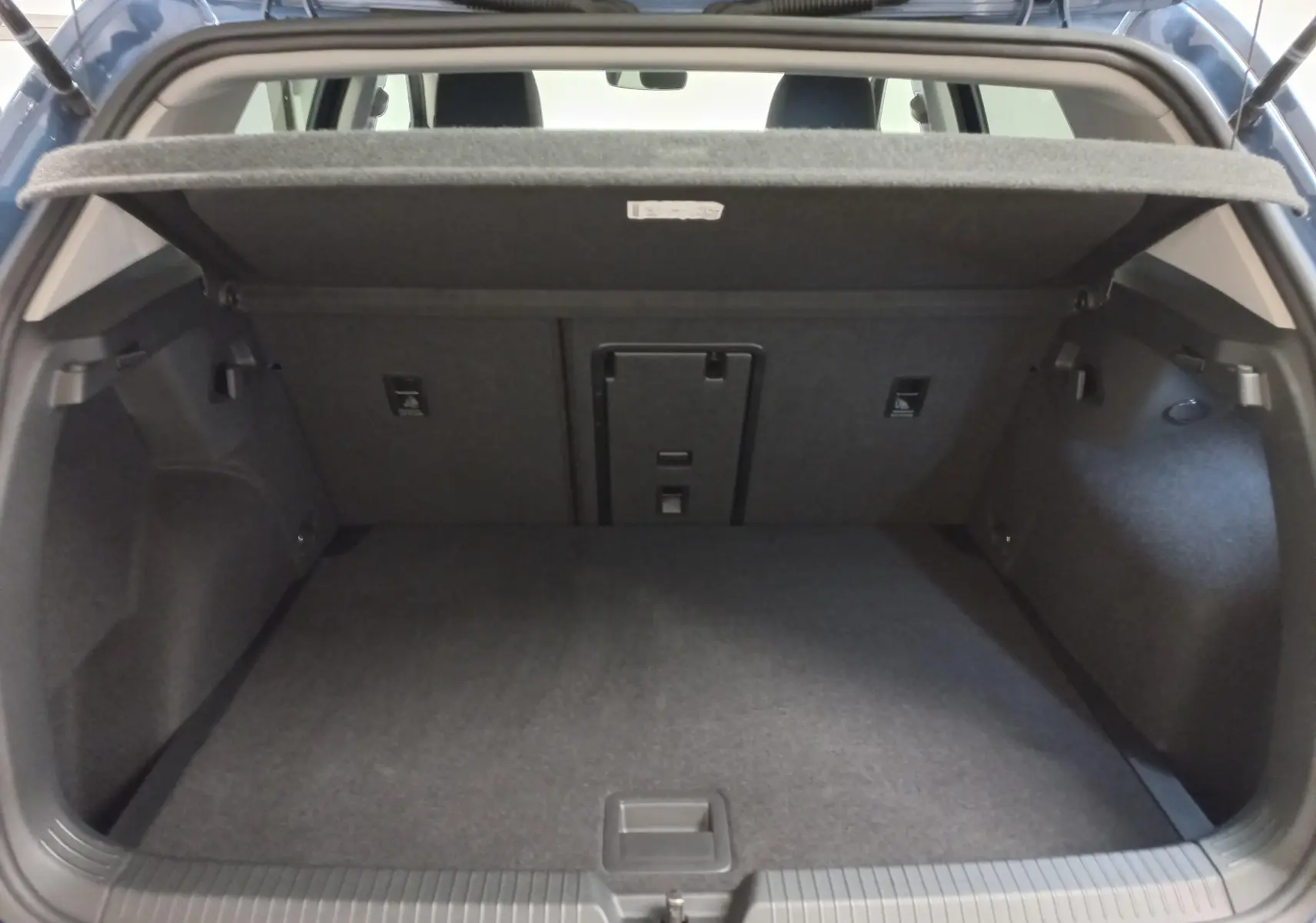 Coffre ouvert d'une Volkswagen Golf 1.5 TSI 116 BVM6 VW Edition 2025, intérieur spacieux et revêtement gris.