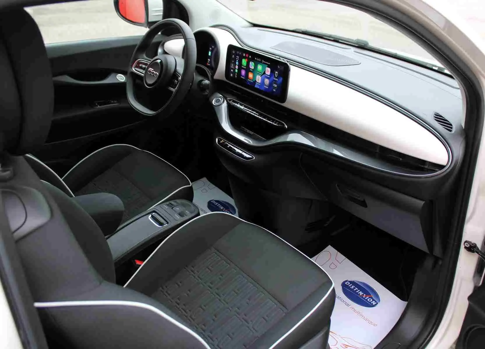 Intérieur avant droit de la Fiat 500 électrique blanche 2023, avec tableau de bord moderne et écran tactile central.