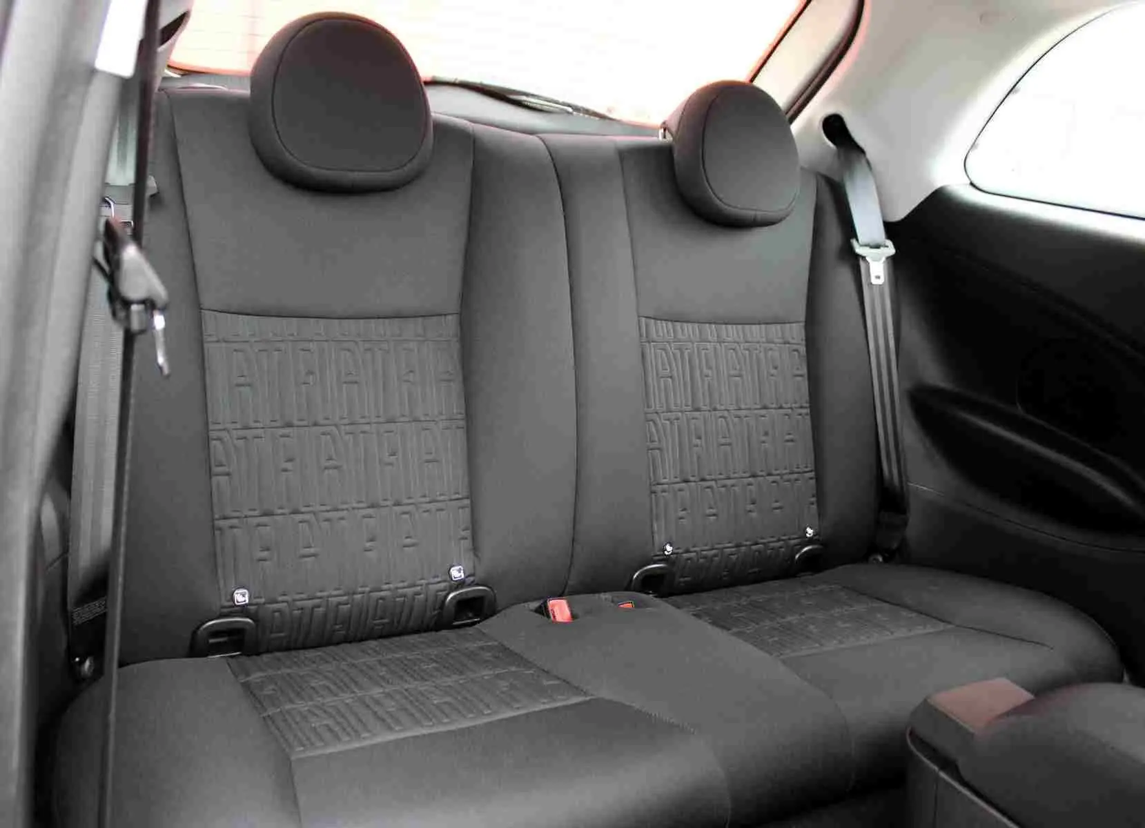 Vue intérieure sur la banquette arrière noire de la Fiat 500 électrique 2023 avec motifs texturés et ceintures visibles.