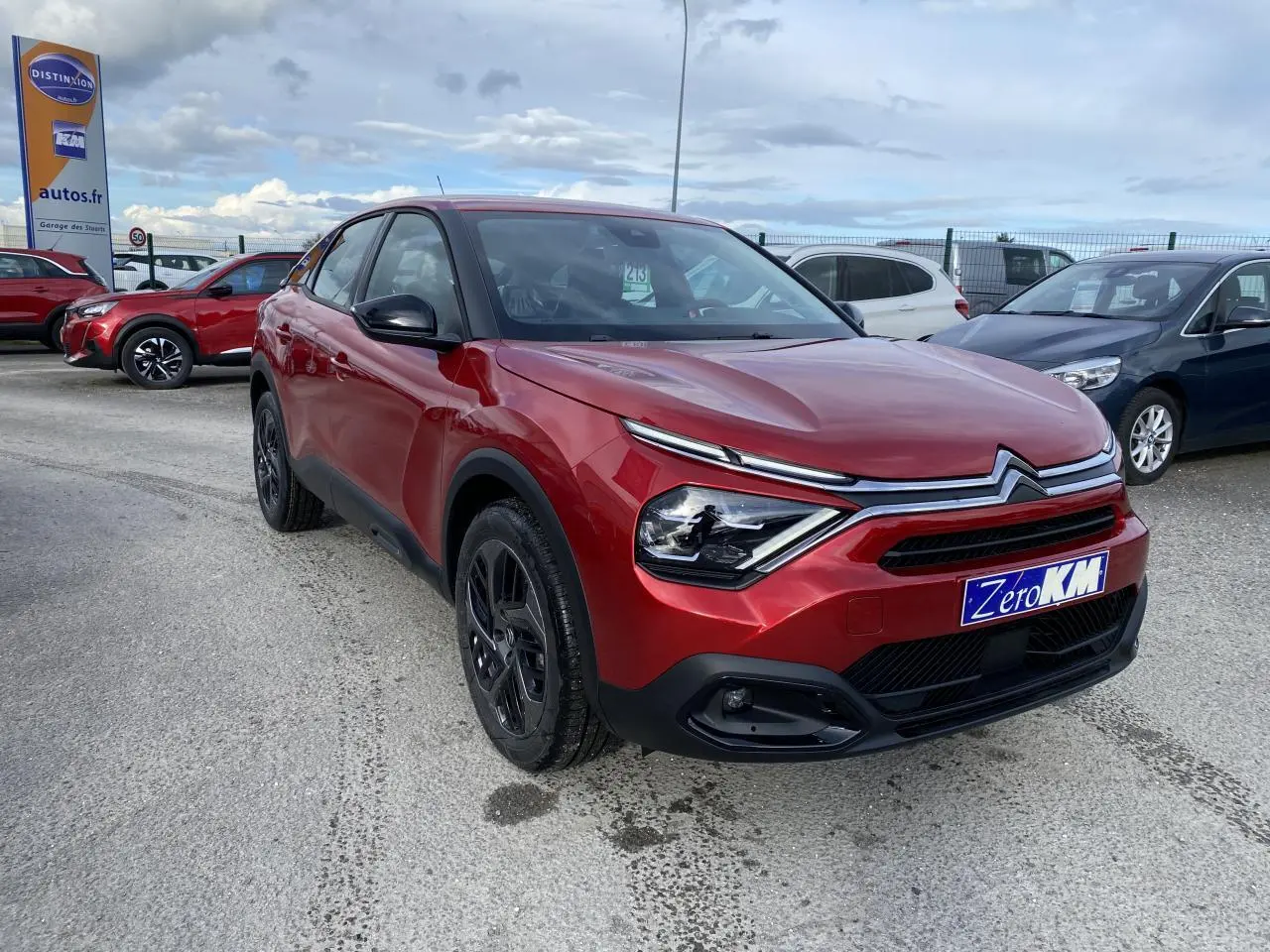 Citroën C4 Rouge Elixir en 3/4 avant droit avec jantes alliage noires et calandre distinctive sur parking.