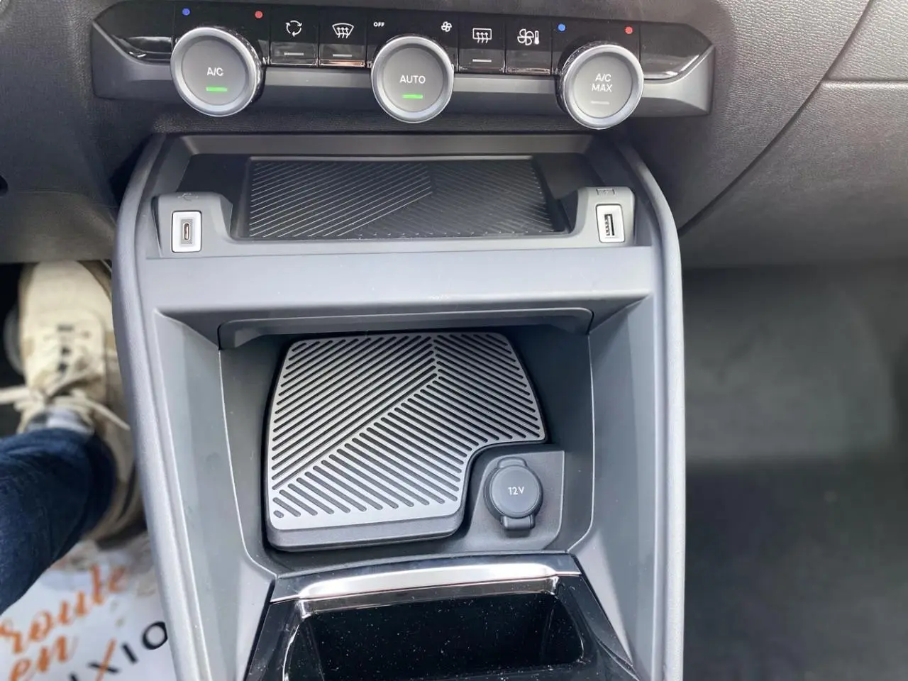 Vue rapprochée de la console centrale de la Citroën C4 2023 avec commandes climatisation et prise 12V visible.