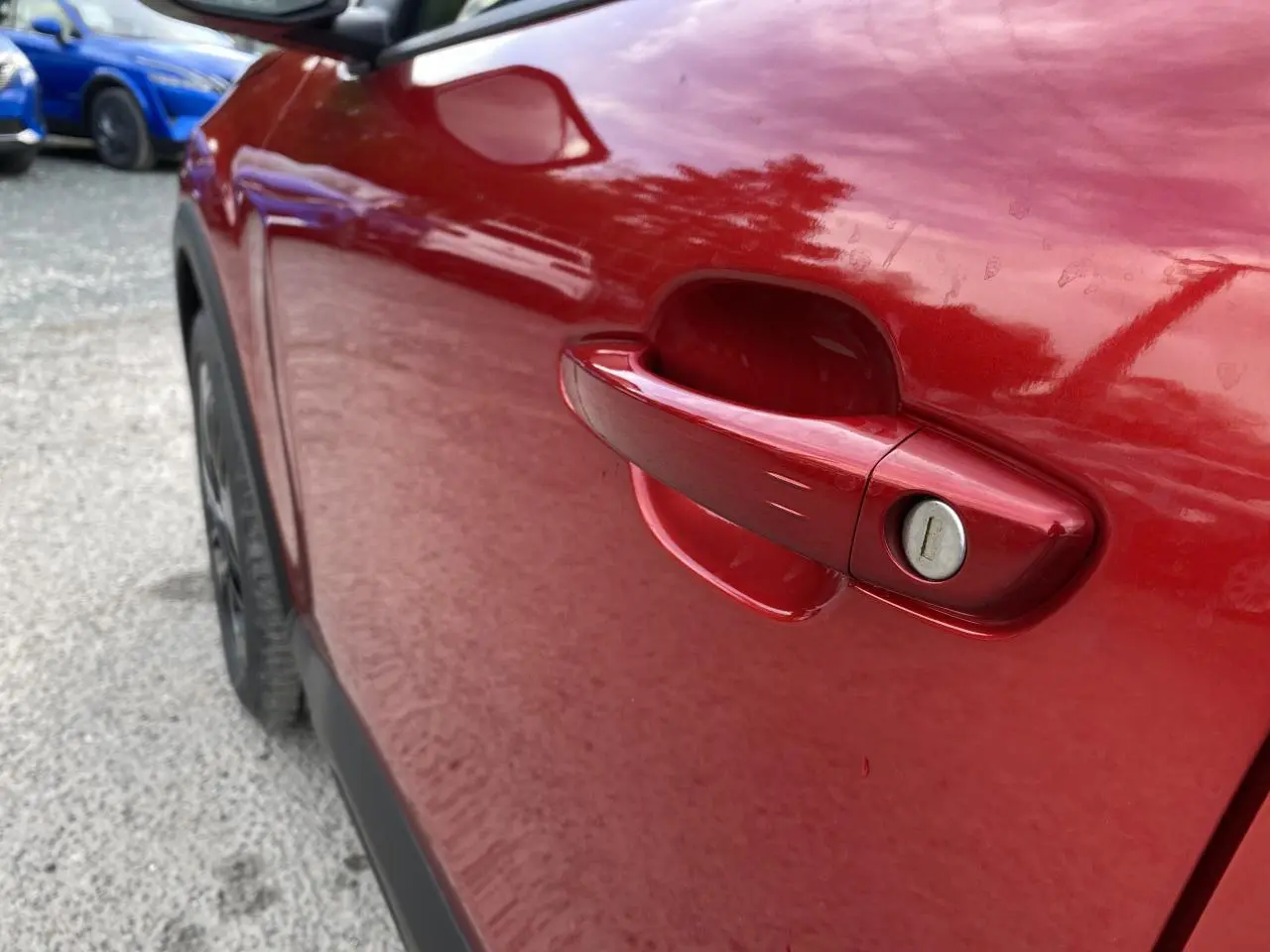 Poignée de porte côté gauche rouge Elixir nacré d'une Citroën C4 2023, avec serrure visible en gros plan.