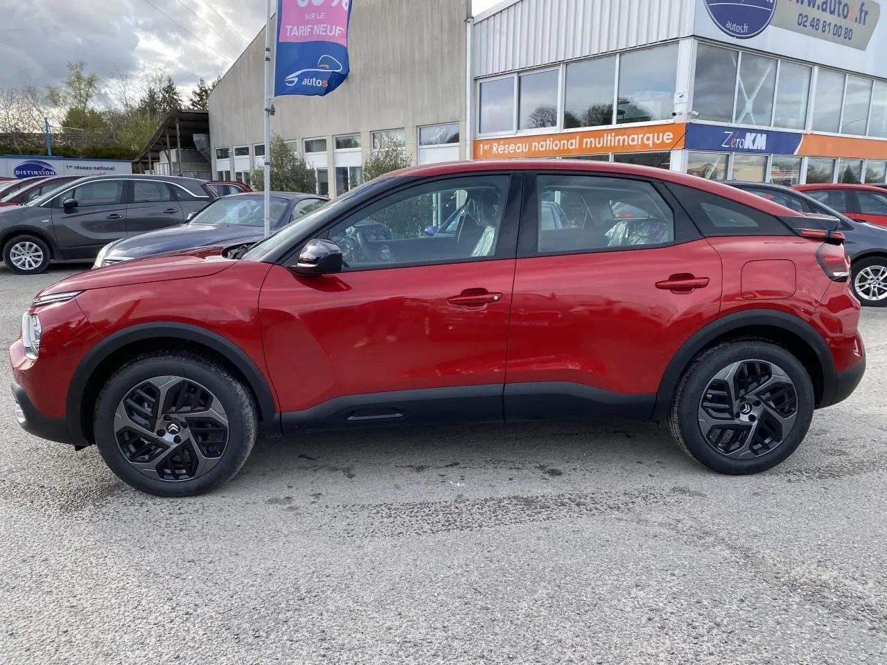 Profil côté gauche d'un Citroën C4 2023 en Rouge Elixir avec jantes alliage 18 pouces et toit noir contrasté.