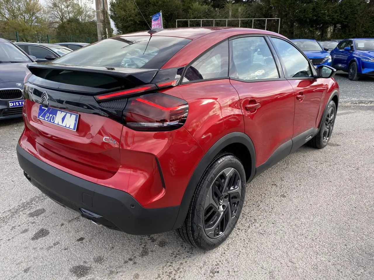 Vue 3/4 arrière droite d'une Citroën C4 2023 rouge Elixir avec jantes alliage noires et toit noir contrasté.