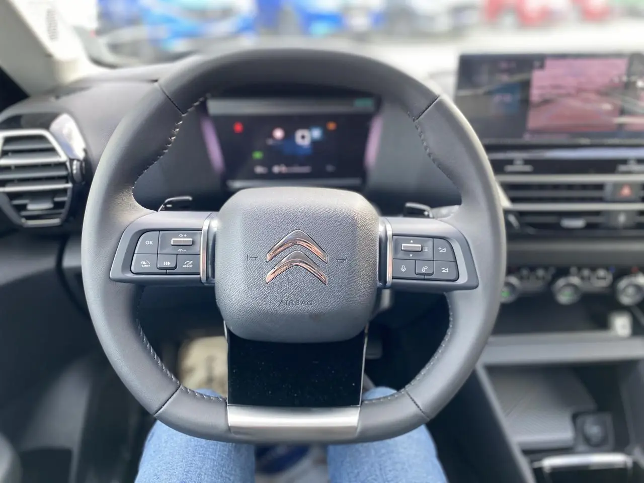 Vue centrée sur le volant du Citroën C4 2023, intérieur noir avec commandes intégrées et écran digital flou.