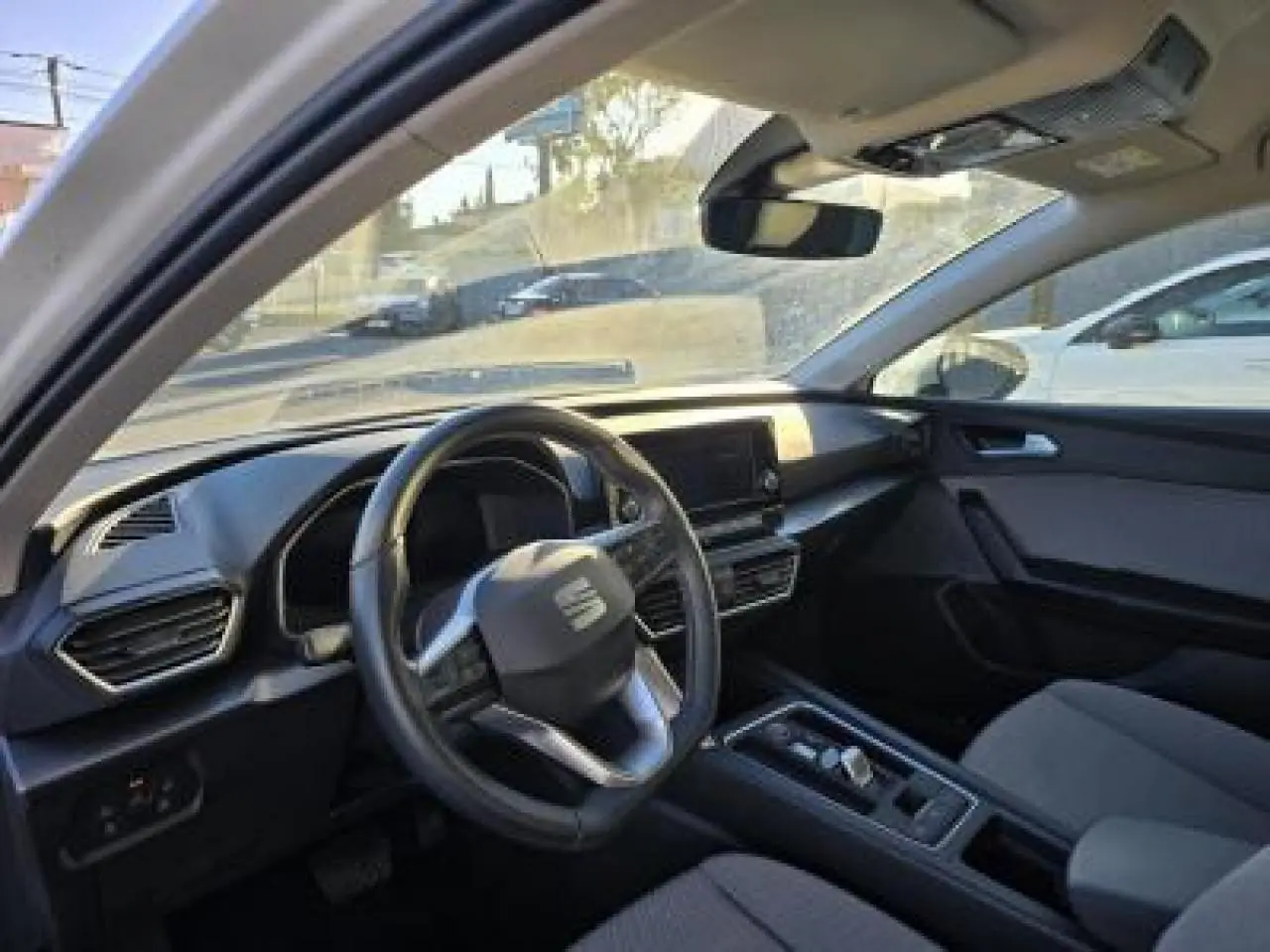 Intérieur de la SEAT LEON blanc, vue côté conducteur, avec tableau de bord moderne et volant cuir multifonction.