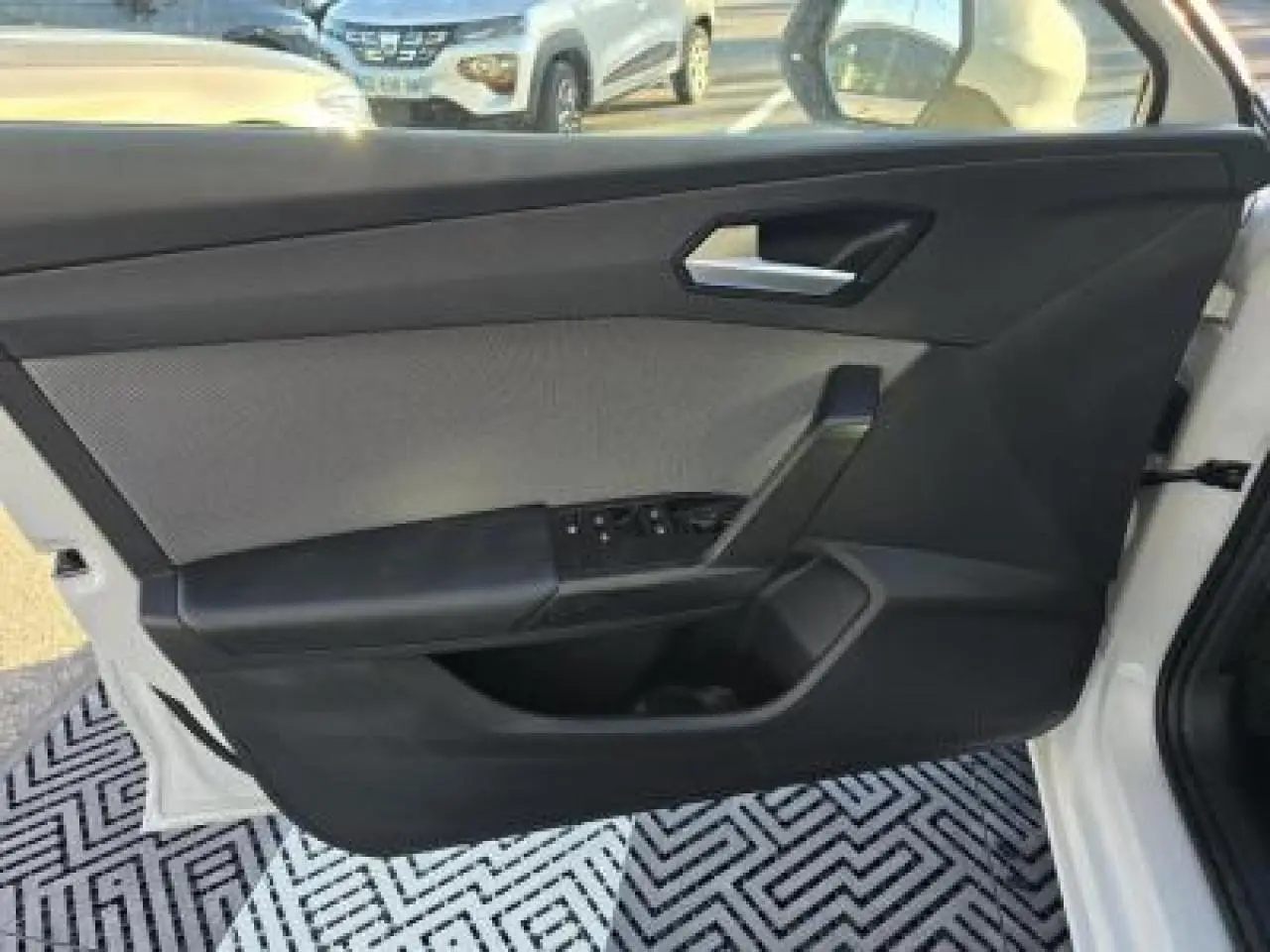Porte côté gauche ouverte d'une SEAT LEON blanche 2024, montrant la garniture intérieure noire et les commandes de vitres.