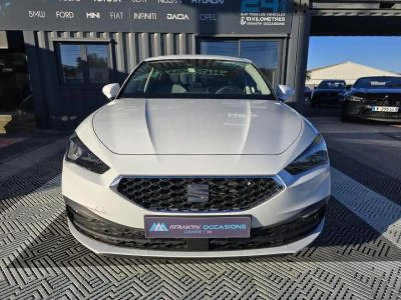 Vue frontale d'une SEAT LEON blanche 2024 avec calandre noire et phares LED anguleux.