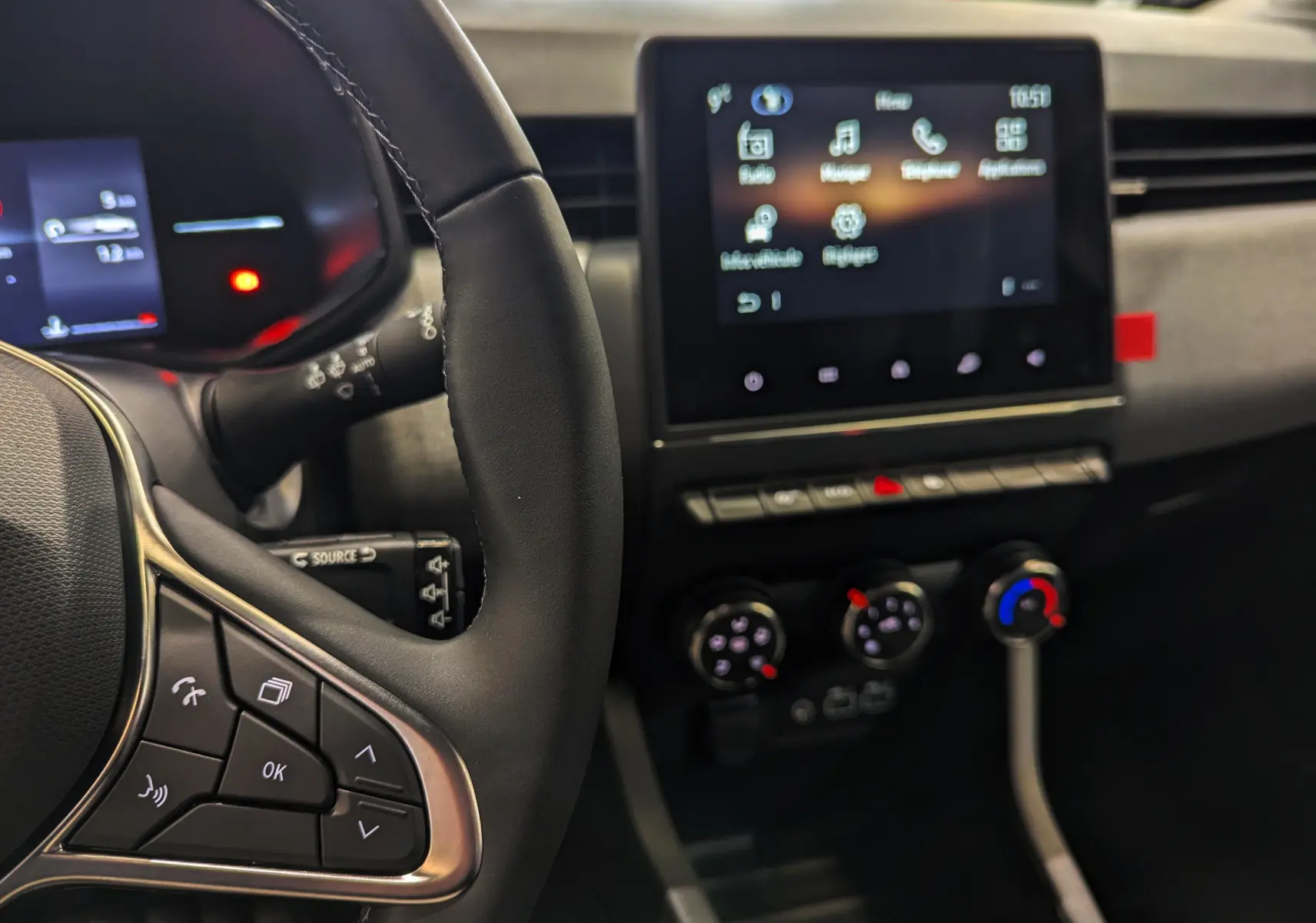 Vue intérieure rapprochée du volant et de l’écran tactile central de la Renault Clio V 2025, finition Evolution, avec commandes au volant visibles.