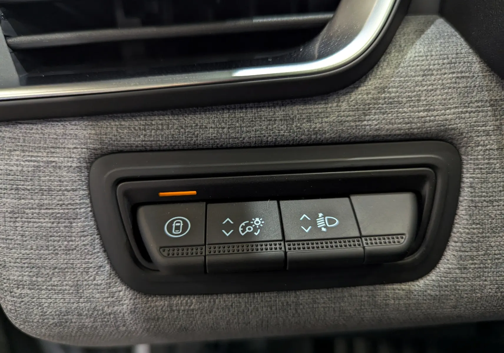 Gros plan sur les commandes de réglage des phares et verrouillage, intérieur tissu gris de la Renault Clio V 2025.