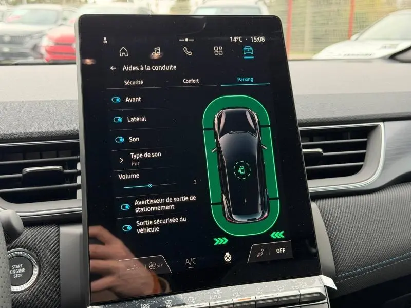 Écran tactile central du Renault Captur 2026 affichant l'aide au stationnement avec vue du véhicule en noir sur fond vert.