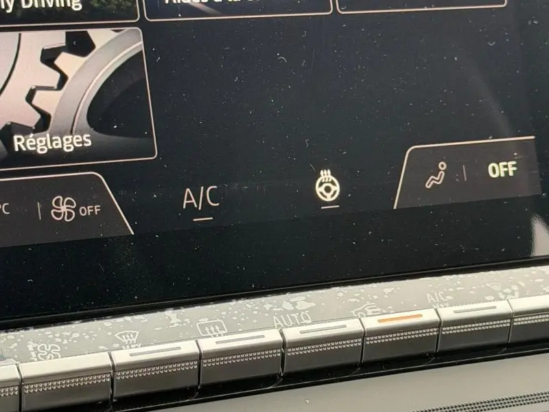 Détail de l'écran tactile du tableau de bord du Renault Captur 2026, affichant les réglages climatisation et volant chauffant.