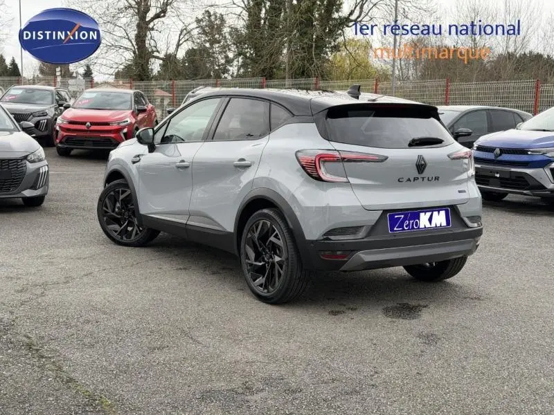 Vue 3/4 arrière droite du Renault Captur 1.8 E-Tech hybride 2026 en Gris Rafale avec toit Noir Étoilé et jantes noires.