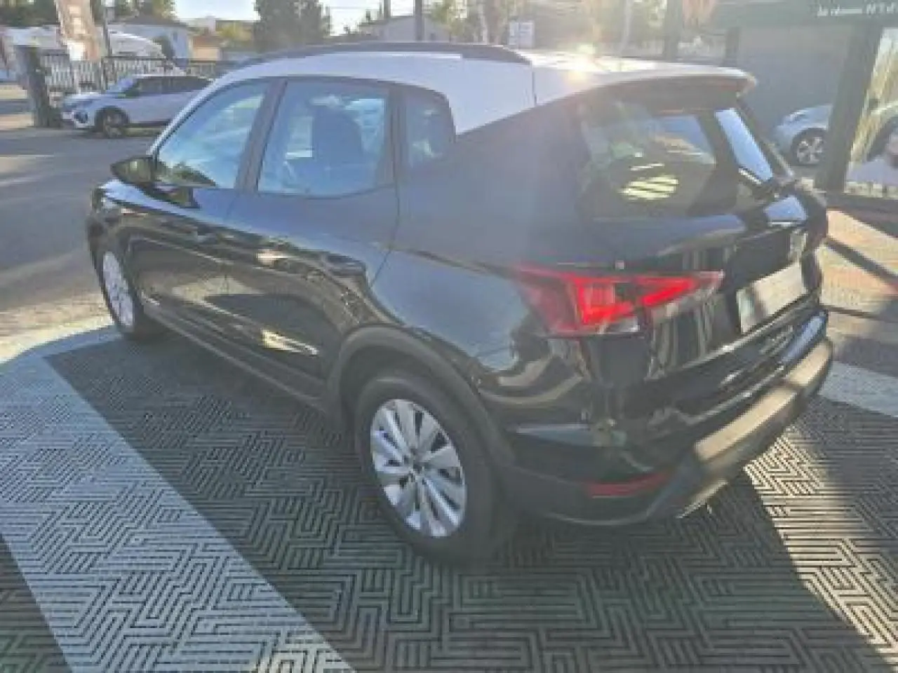 Vue 3/4 arrière droite d'un SEAT Arona noir minuit avec toit contrasté, jantes alliage et feux arrière LED allumés.