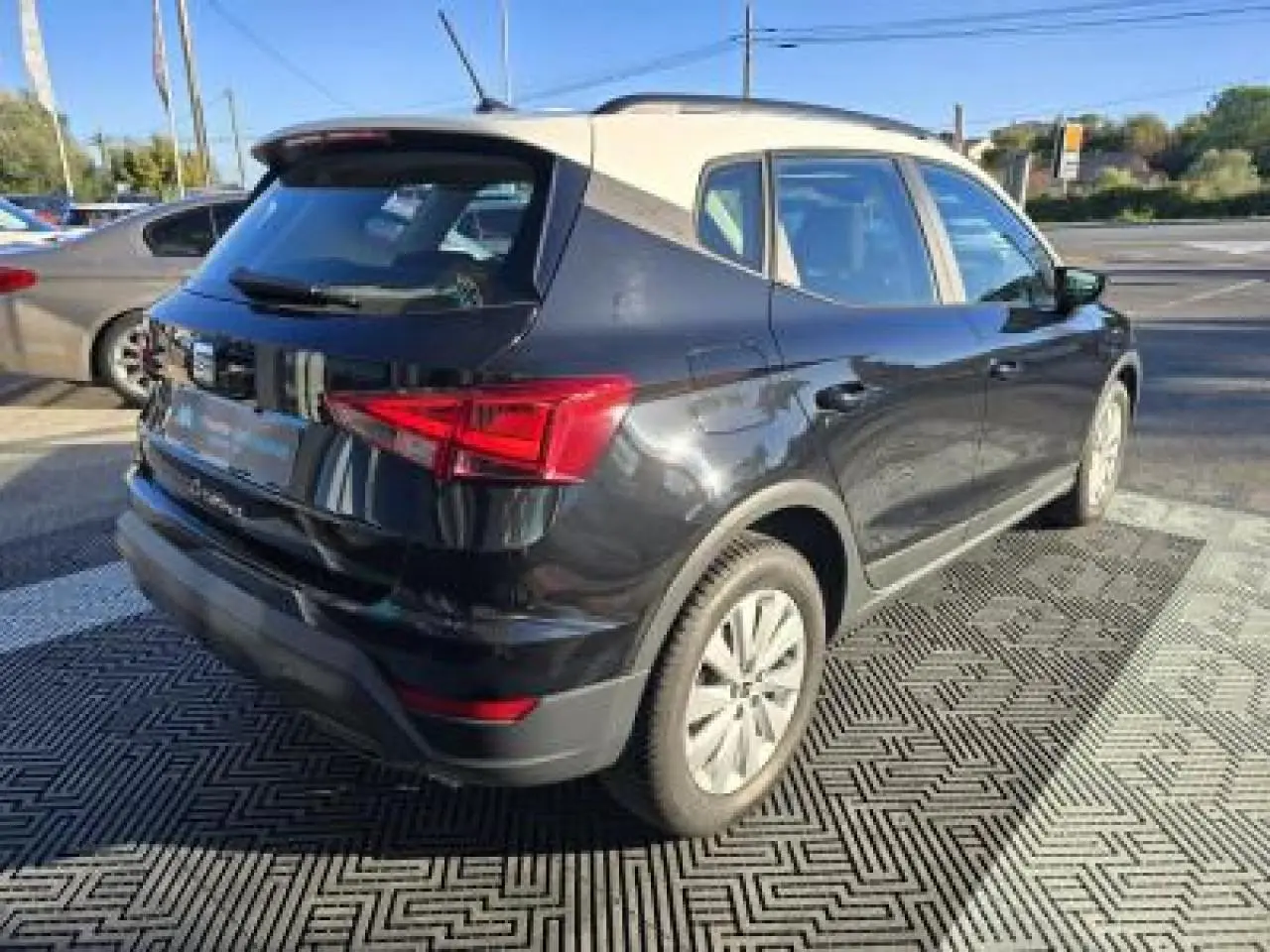 SEAT Arona 2024 noir minuit avec toit contrasté, vue 3/4 arrière côté gauche sur parking extérieur.