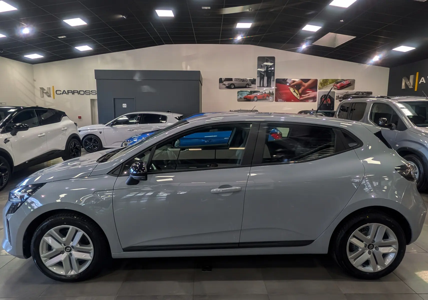 Renault Clio V Blue dCi 100 ch gris Rafale vue de profil côté gauche en intérieur, jantes alliage et rétroviseurs noirs.