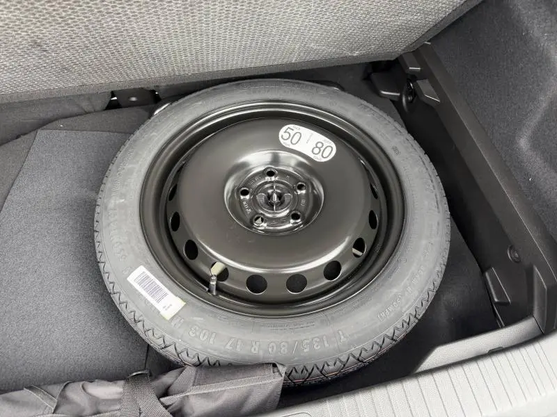 Roue de secours noire vue de dessus dans le coffre d'un Renault Captur 1.8 E-Tech full hybrid 2026 Bleu Iron/Noir Etoilé.