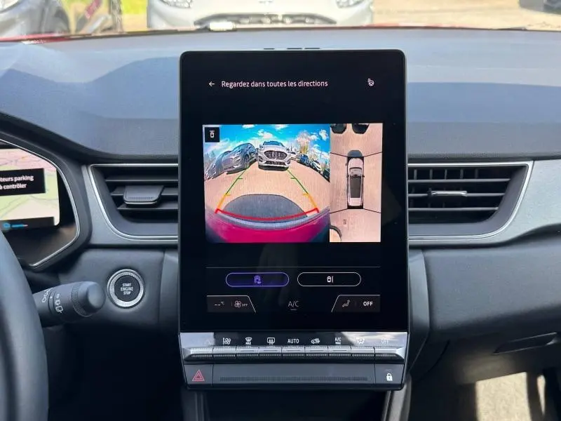 Vue intérieure du tableau de bord du Renault Captur rouge 2025, écran tactile affichant la caméra de recul et vue 360° parking.