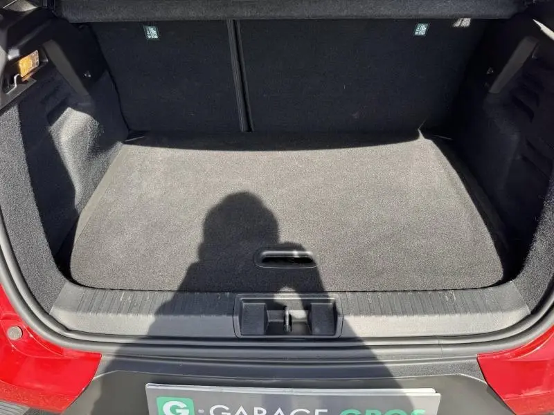 Vue du coffre ouvert d'un Renault Captur rouge flamme 2025, montrant un espace de rangement propre et bien fini.