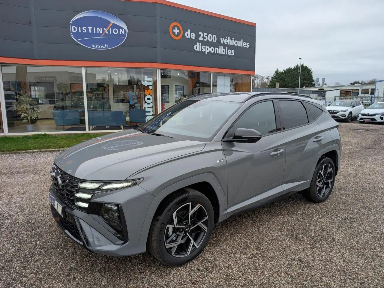 Vue 3/4 avant droite d’un Hyundai Tucson gris métallisé N Line avec jantes alliage 19 pouces et vitres teintées.