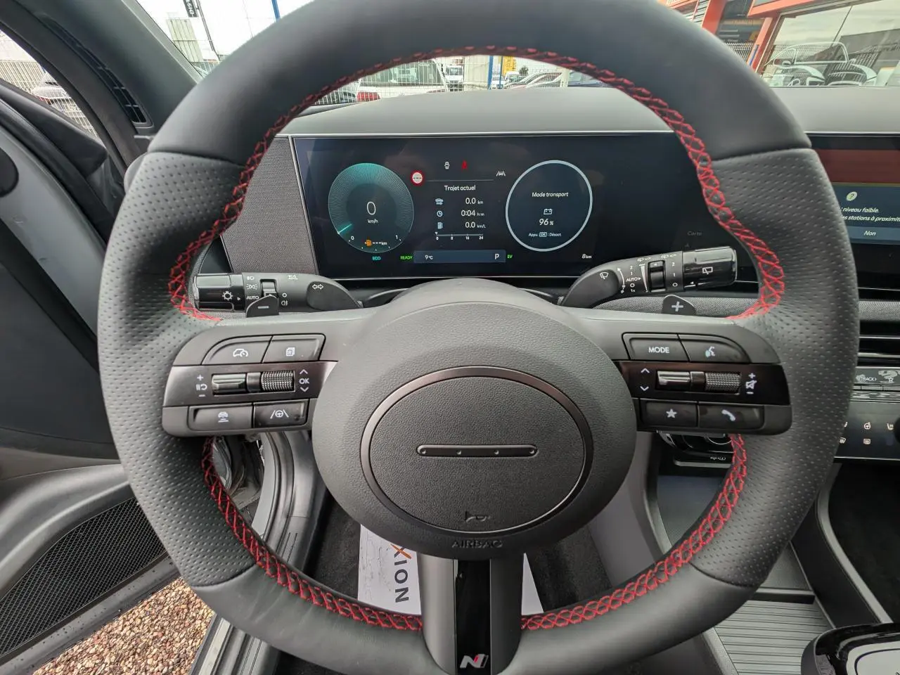 Vue centrée sur le volant cuir noir avec surpiqûres rouges et tableau de bord numérique du Hyundai Tucson gris N Line.