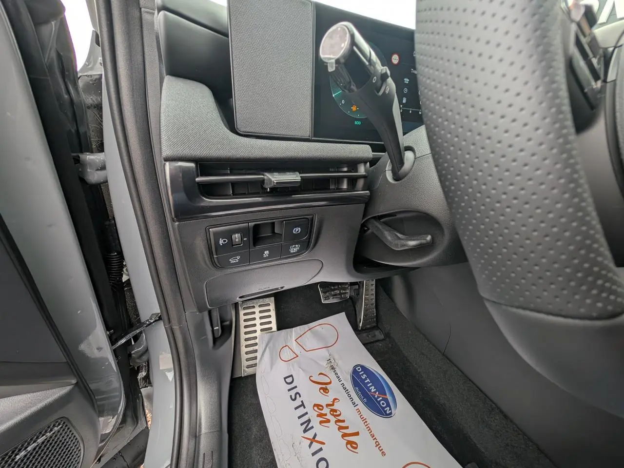 Vue rapprochée côté gauche du poste de conduite du Hyundai Tucson gris, avec pédalier aluminium et commandes sous tableau de bord.