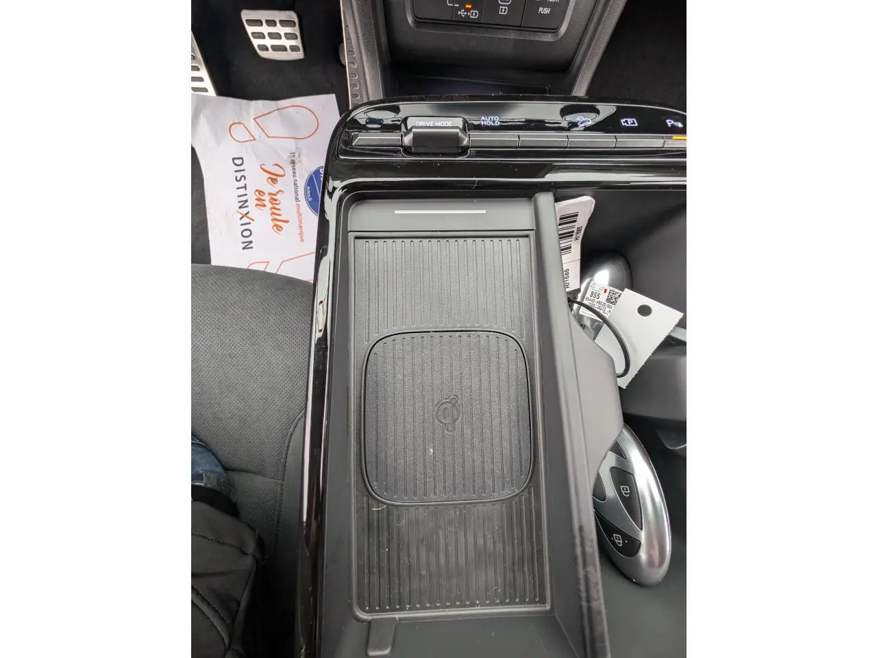 Vue rapprochée de la console centrale noire avec chargeur sans fil et commandes de modes de conduite du Hyundai Tucson gris.