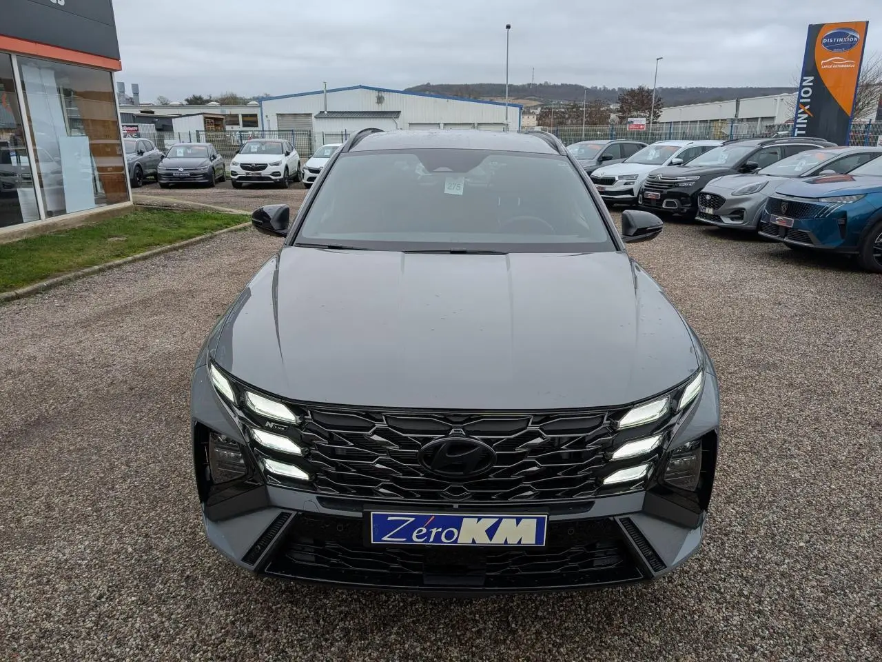 Vue frontale d’un Hyundai Tucson gris métallisé avec calandre noire N Line et feux LED allumés.