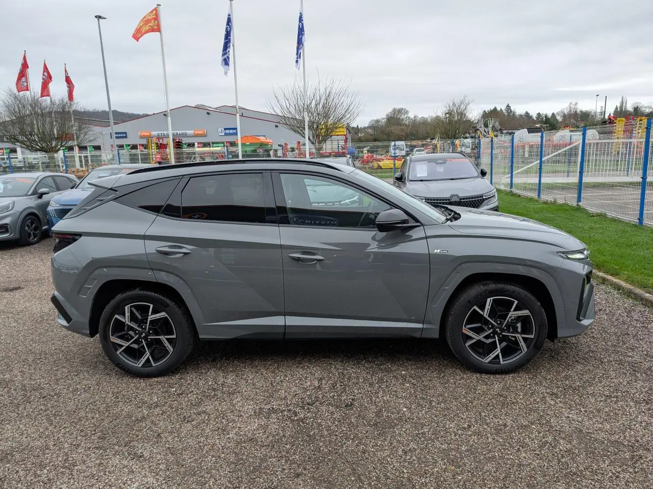 Profil côté gauche d’un Hyundai Tucson gris métallisé N Line 2026 avec jantes alliage 19 pouces et vitres surteintées.