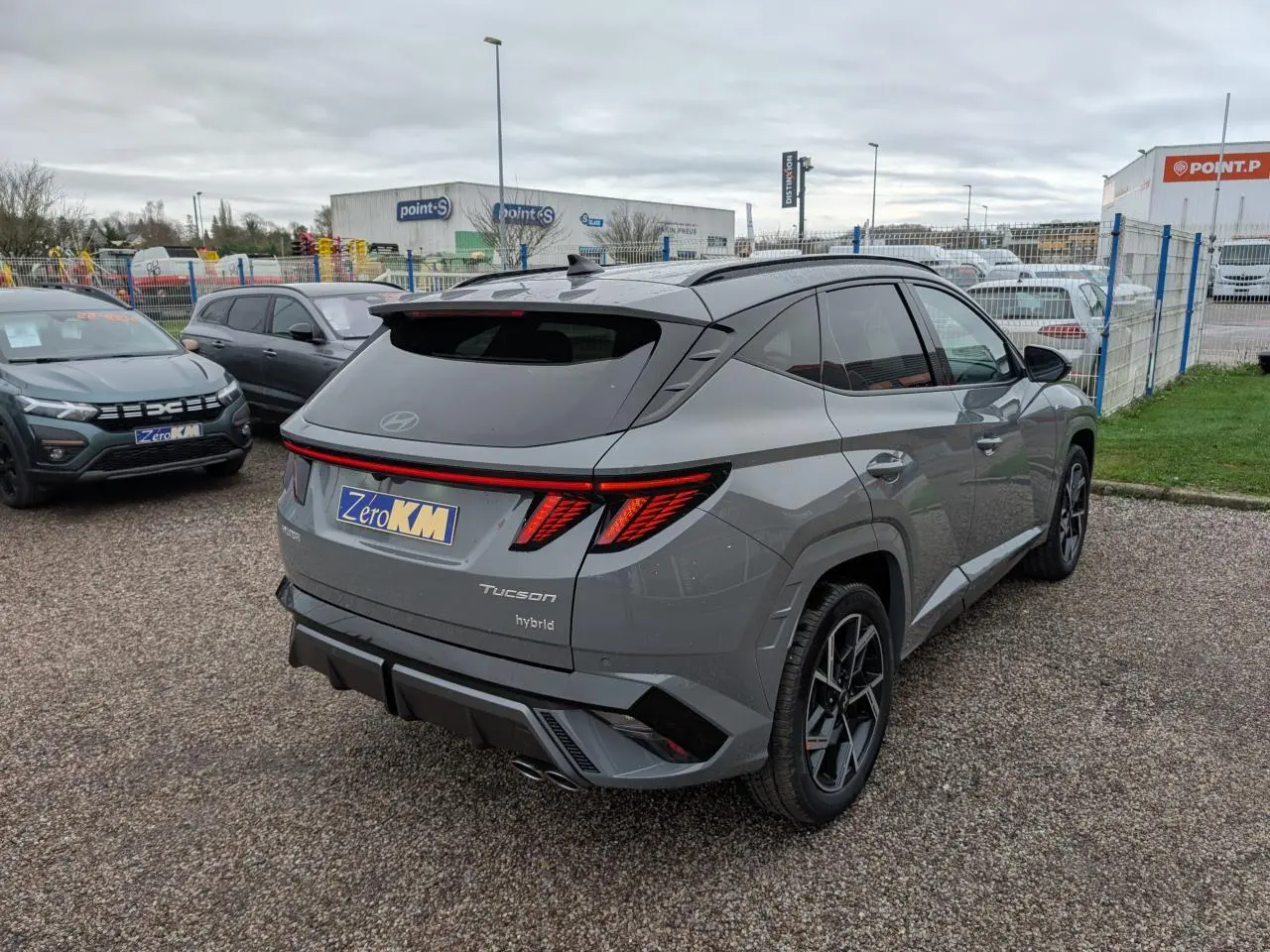 Vue 3/4 arrière droite d'un Hyundai Tucson gris métallisé avec feux arrière LED et double sortie d'échappement.