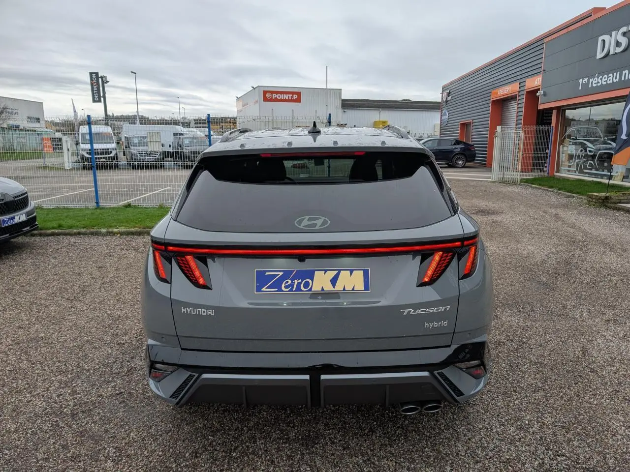 Vue arrière d’un Hyundai Tucson gris métallisé avec feux arrière LED en bandeau et double sortie d’échappement.