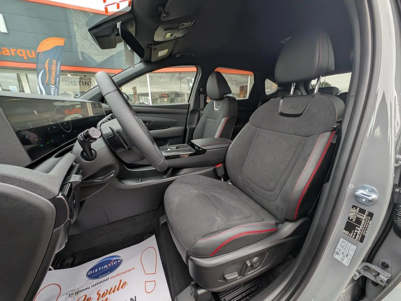 Vue intérieure côté conducteur du Hyundai Tucson gris 2026, sièges N Line en cuir/alcantara avec surpiqûres rouges.