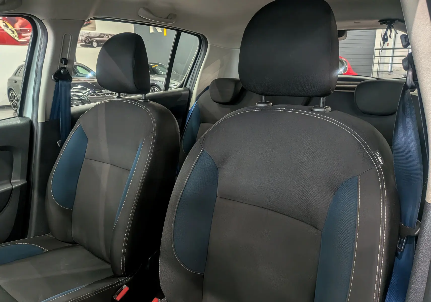 Gros plan sur les sièges avant en tissu noir et bleu de la Dacia Sandero TCe 90 CH SL 10 ANS blanche, vue intérieure côté droit.