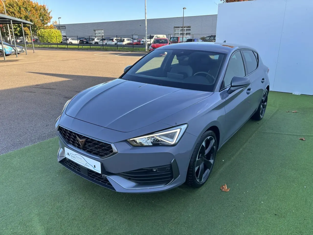 Vue 3/4 avant d'une CUPRA Leon 2024 gris Graphene avec jantes alliage noires et feux LED distinctifs.