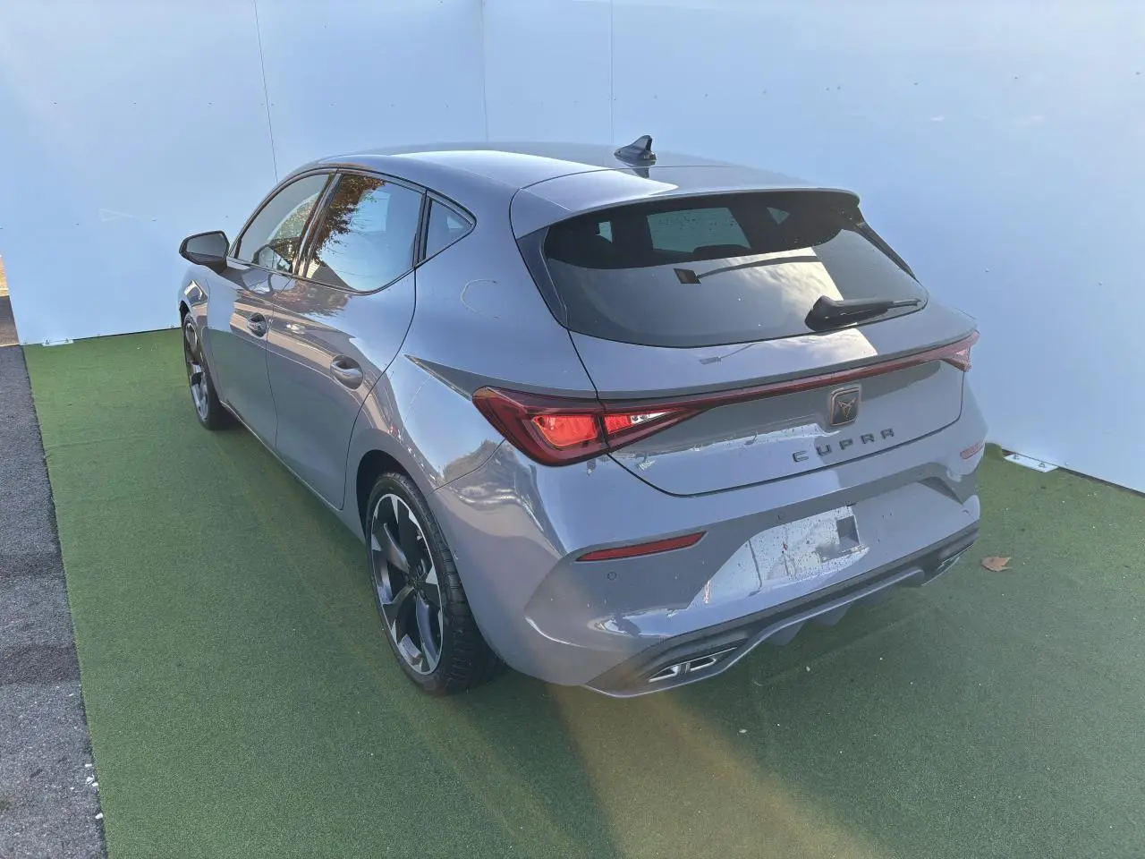 Vue 3/4 arrière droite d'une CUPRA Leon 2024 gris Graphene avec feux LED et jantes alliage 18 pouces.
