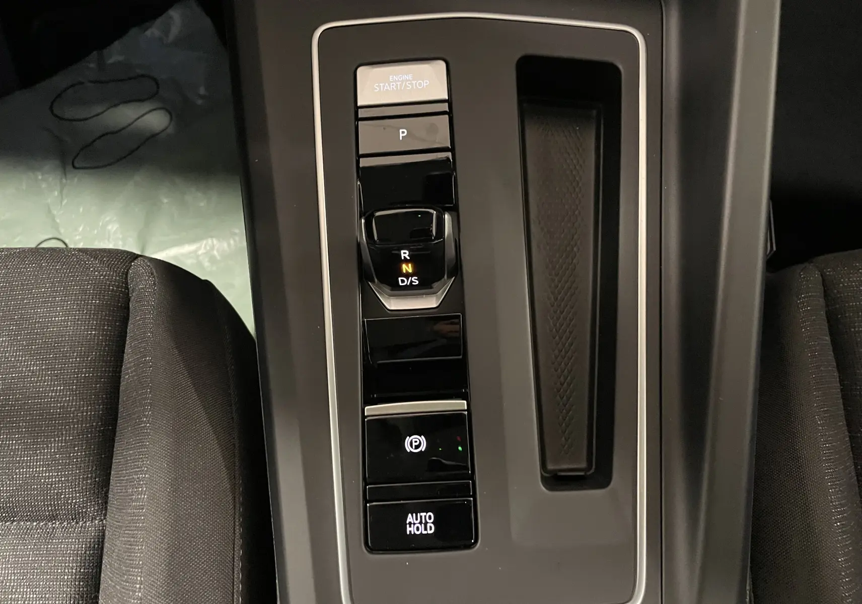 Console centrale noire avec levier de vitesses automatique et boutons start/stop, frein à main et auto hold dans une Volkswagen Golf 2023